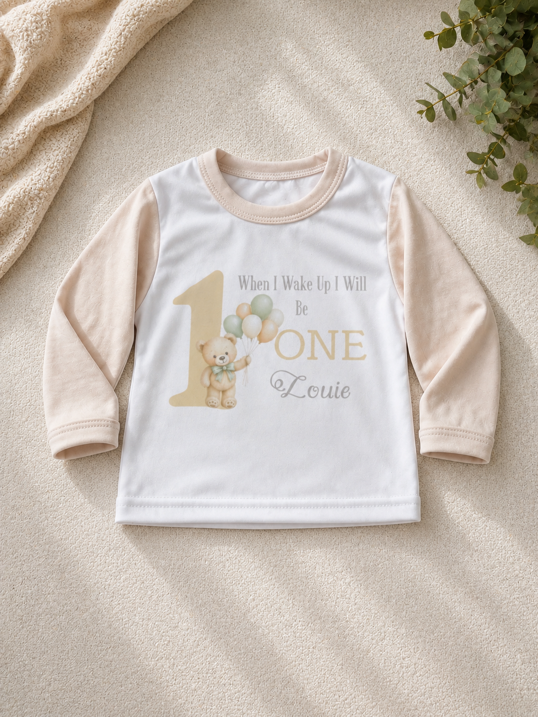 Personalised birthday pyjama set laid flat showing teddy bear and balloon design with name Louie
