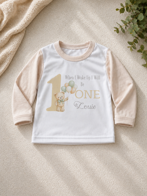 Personalised birthday pyjama set laid flat showing teddy bear and balloon design with name Louie